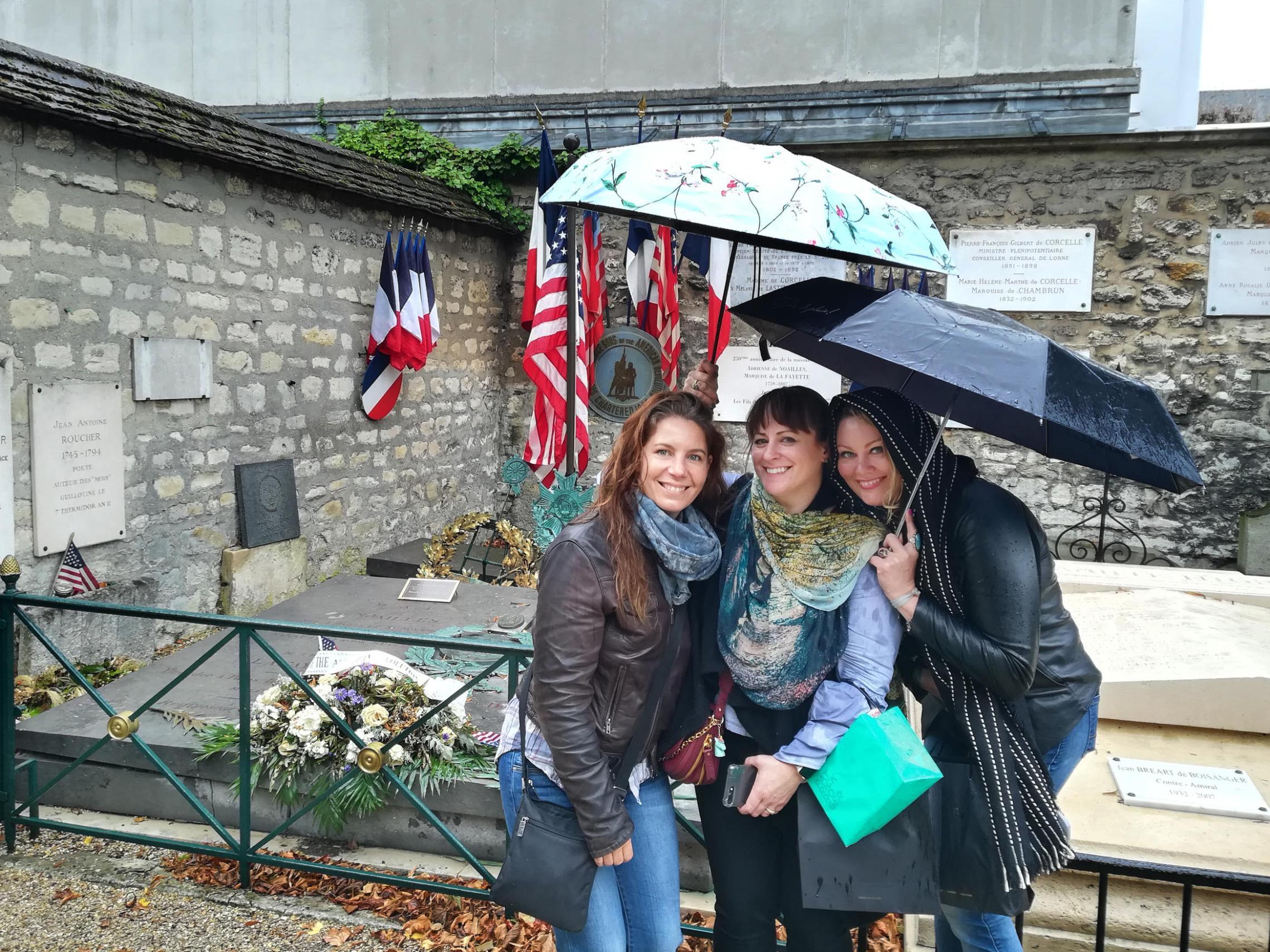 Three women posing in front of a memorial