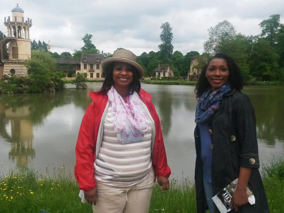 Two women standing next to a lake